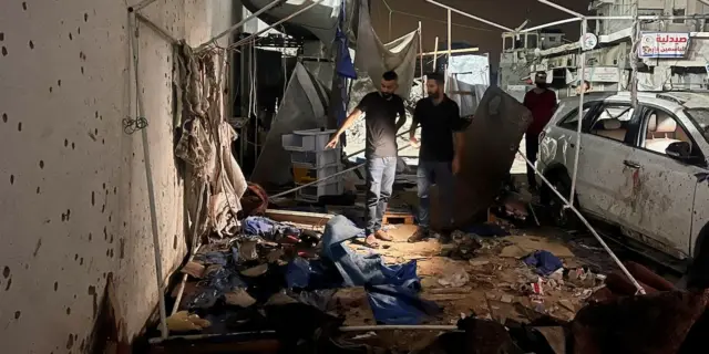 Two Palestinian men look at the scene where five journalists were killed on Sunday in an Israeli air strike