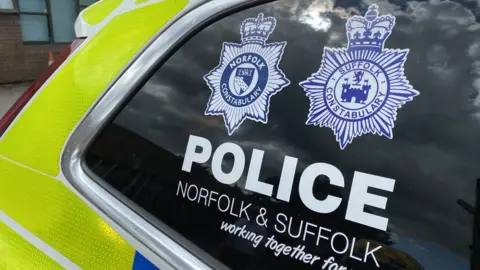 Ben Parker/BBC A close-up of a police car window with the Norfolk and Suffolk police crests on it.