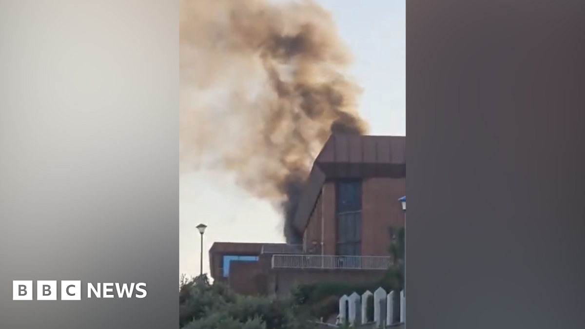 Smoke rising from the top of the red brick building with a distinctive brown flat roof