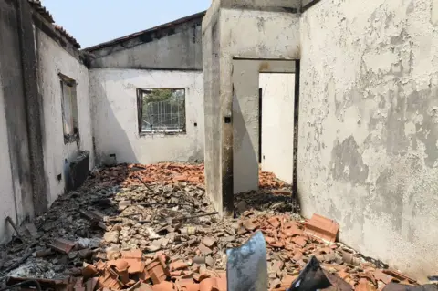 Ben Armstrong A room in the home showing the extent of the damage. There is no roof on the room and the floor is completely covered in brick and rubble. Ash covers the walls, the windows are completely smashed through. 