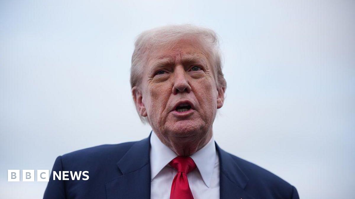 Headshot of Donald Trump talking. He is wearing a dark suit jacket, white shirt and red tie.