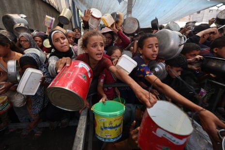 Palestinians gather to receive cooked meals from a food distribution centre in the Nuseirat refugee camp in the central Gaza Strip on 18 August 2025.