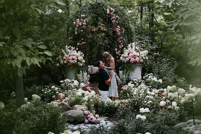 Couple sharing a romantic moment in a lush garden surrounded by flowers, highlighting Travis Kelce’s ex Kayla Nicole buzz.