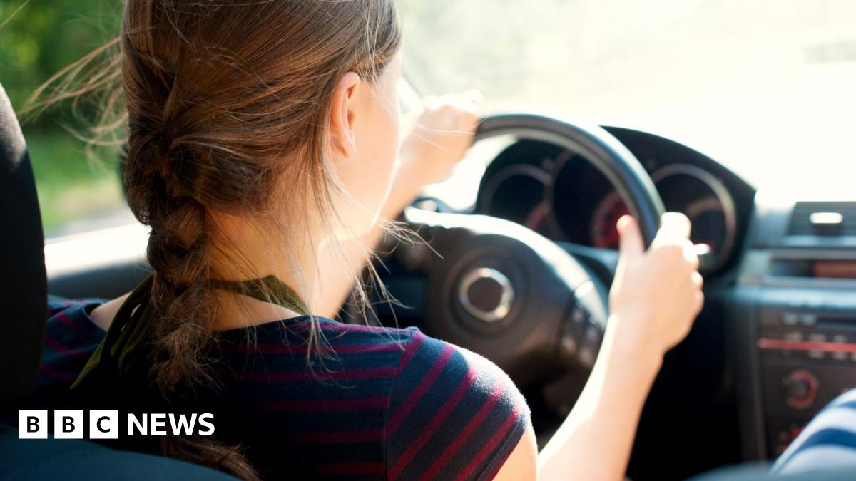 Rear view of teenage girl, who wears her hair in a plait, driving car.