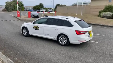 A white taxi, said to be carrying Lucy Connolly, is pictured driving away from the prison