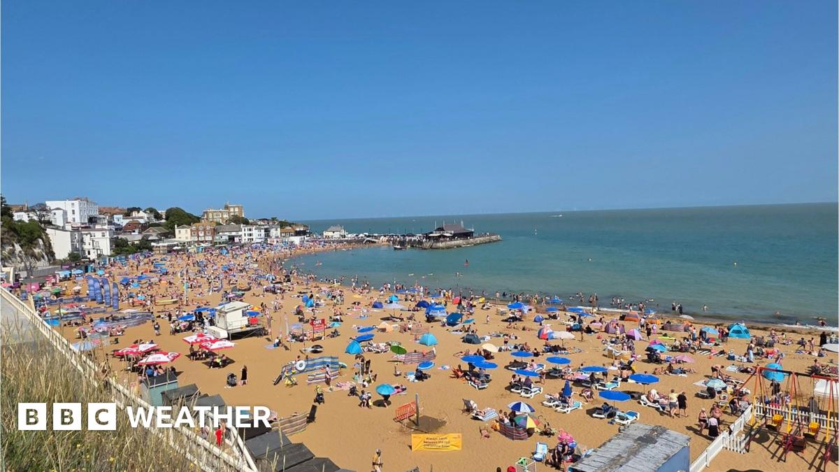 Busy view over sandy beach in Broadstairs, Kent with lots of parasols and sunbathers