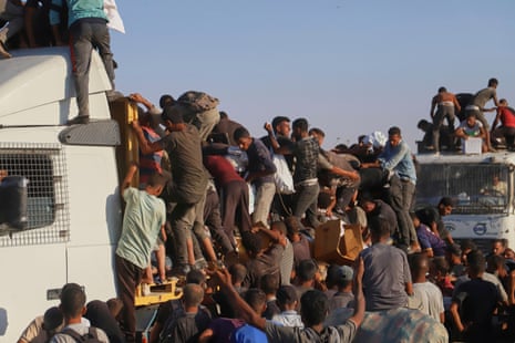 Many people climbing on to the back of an aid truck