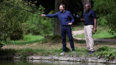 PA Media Foreign Secretary David Lammy fishing with US vice president JD Vance at Chevening House in Kent. Both men are wearing blue shirts, JD Vance is in jeans and Lammy is in beige chinos.