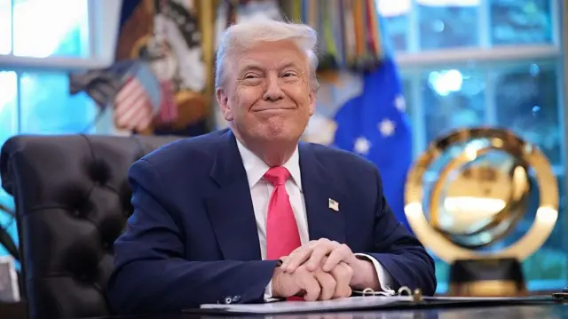 US President Donald Trump sitting and smiling