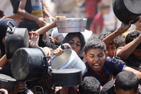 Palestinian people gather to receive hot meals distributed by a charity in Gaza City.