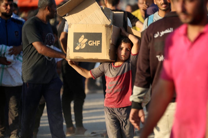 A young boy carries an aid parcel from the privately-run Gaza Humanitarian Foundation near the Nuseirat refugee camp in central Gaza, on June 25, 2025.