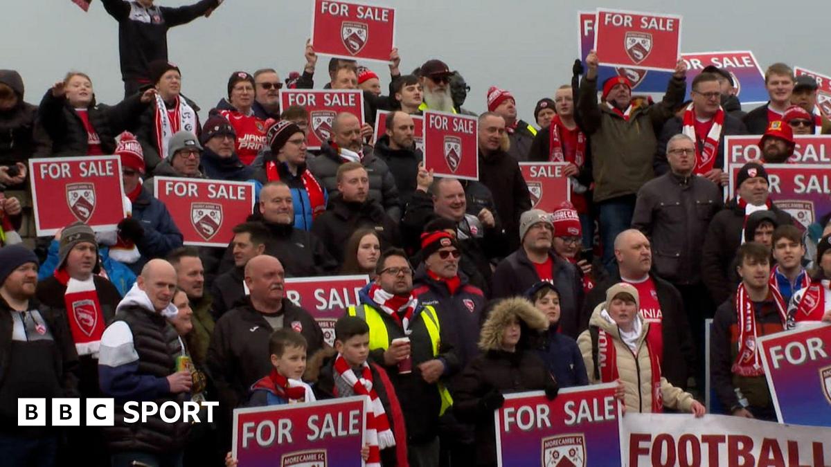 Morecambe fans hold protests signs during a match