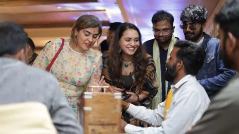 Third Place People wearing traditional Indian clothes participate in games at a fake wedding party 