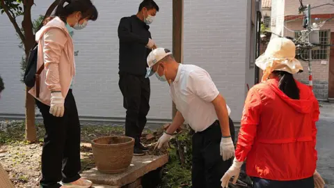 Getty Images Four workers inspecting a neighbourhood in Foshan amid a sharp rise in chikungunya fever cases 