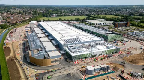 Getty Images A large white data centre building under construction in Hertfordshire, surrounded by green land, a river and housing estates further afield.