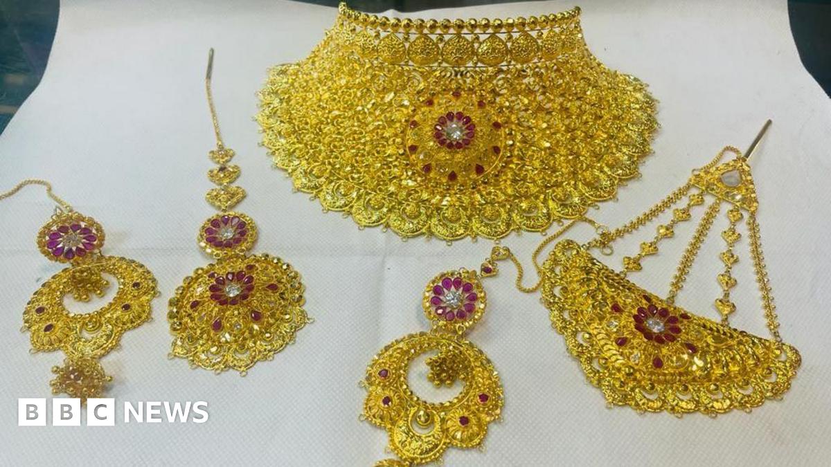 A gold necklace and other items of jewellery with pink stones inset in floral patterns.