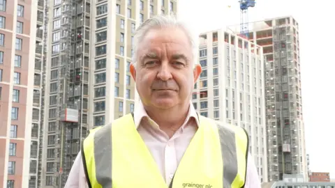 Mike Keaveny, a man in a hi-viz tabard, looks at the camera