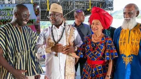 EPA Prime Minister of Trinidad and Tobago, Kamla Persad-Bissessar dressed in Nigerian-inspired clothed stand with other dignitaries.