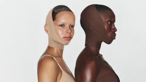 Skims Two women wearing a face wrap that goes under their chins to the top of their heads