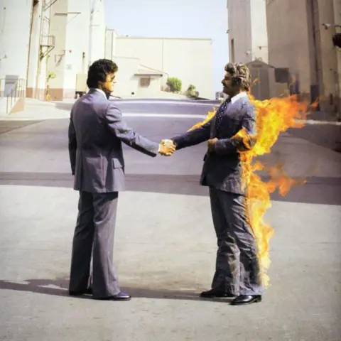 Rahman Hassani/SOPA Images/LightRocket via Getty Images Two men wearing suits shake hands - one of them is on fire