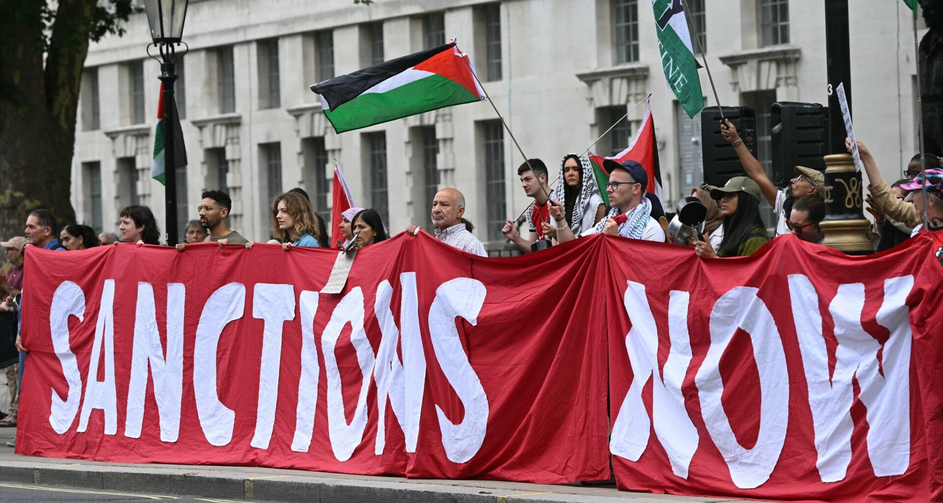Protesters hold a banner calling for sanctions to be placed on Israel during a demonstration in support of Palestinians in Gaza amid fears of starvation in the war-torn territory outside Downing Street in London on July 29, 2025. (JUSTIN TALLIS / AFP)