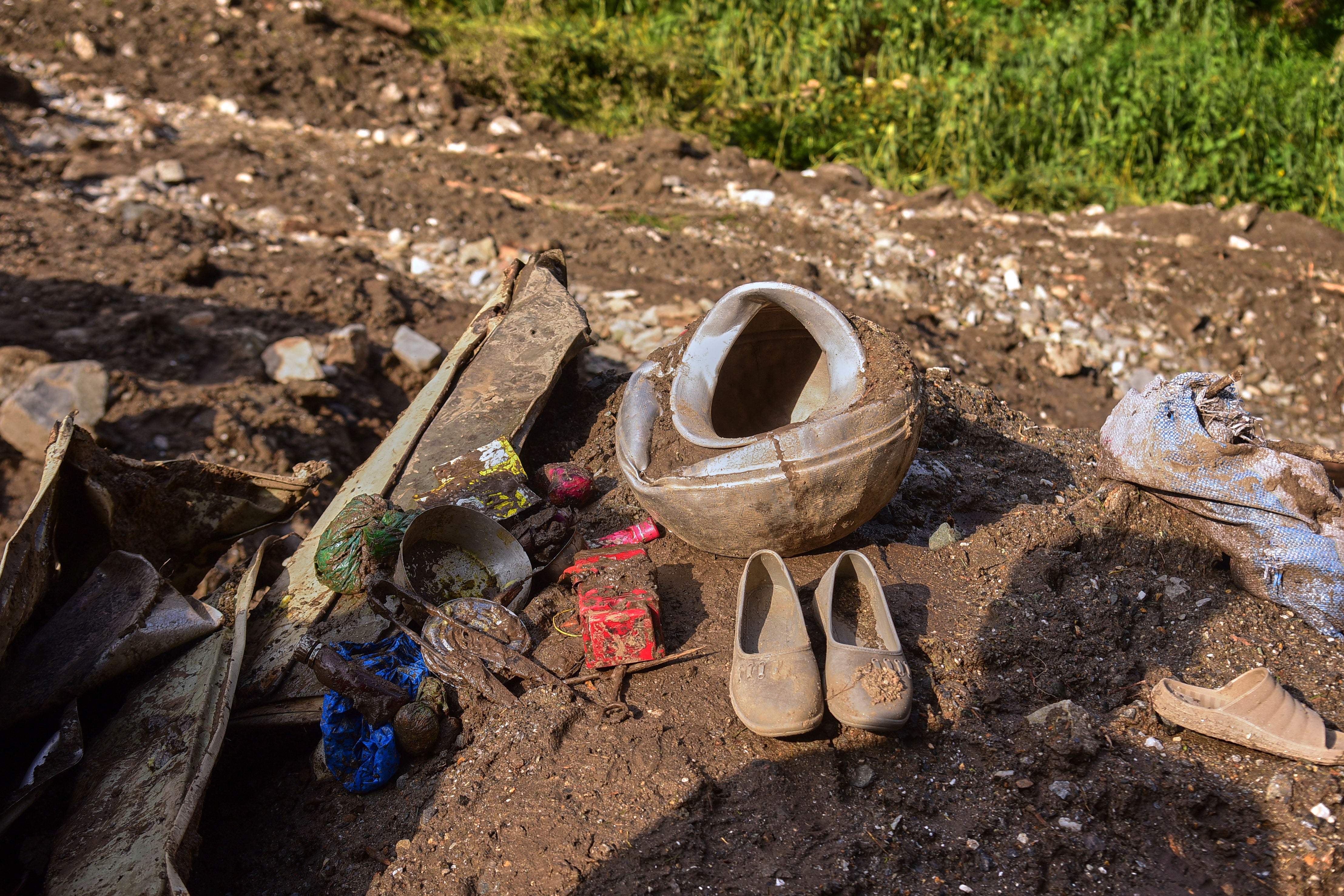 Shoes and other household items are seen on the debris of damaged houses at the incident site of cloudburst that triggered flash flood, in Naryan Behak village near Muzaffarabad, the main town of Pakistan's controlled Kashmir, Friday, Aug. 15, 2025. (AP Photo/M.D. Mughal)
