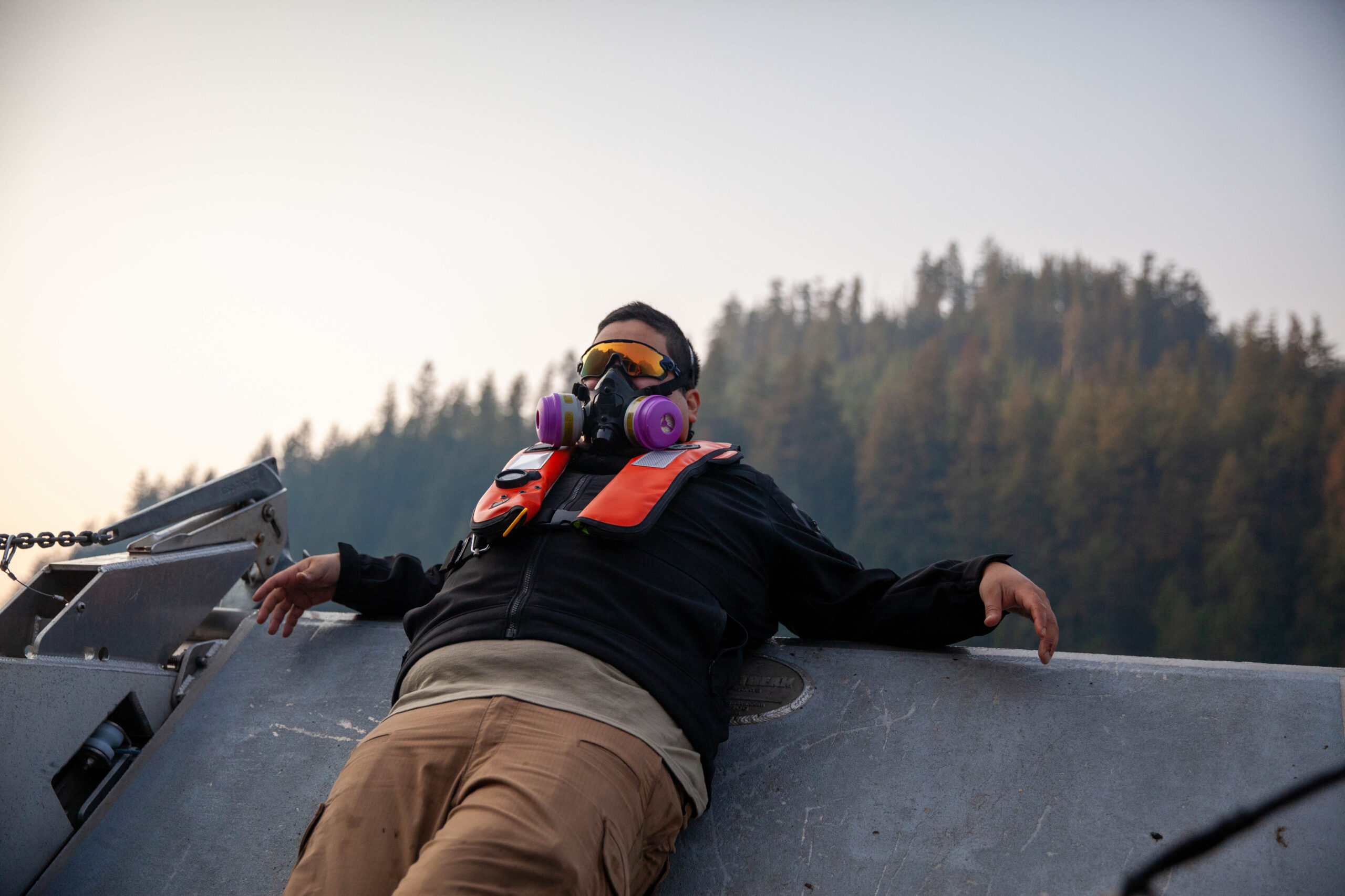 Travis George, who wears sunglasses and a respirator, rests on the landing ramp of the nation's research vessel