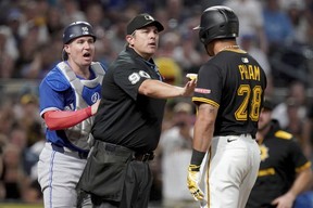 Home plate umpire Mark Ripperger, center, gets between Toronto Blue Jays catcher Tyler Heineman, left, and Pittsburgh Pirates' Tommy Pham, right, during the seventh inning of a baseball game Monday, Aug. 18, 2025, in Pittsburgh. (AP Photo/Matt Freed)