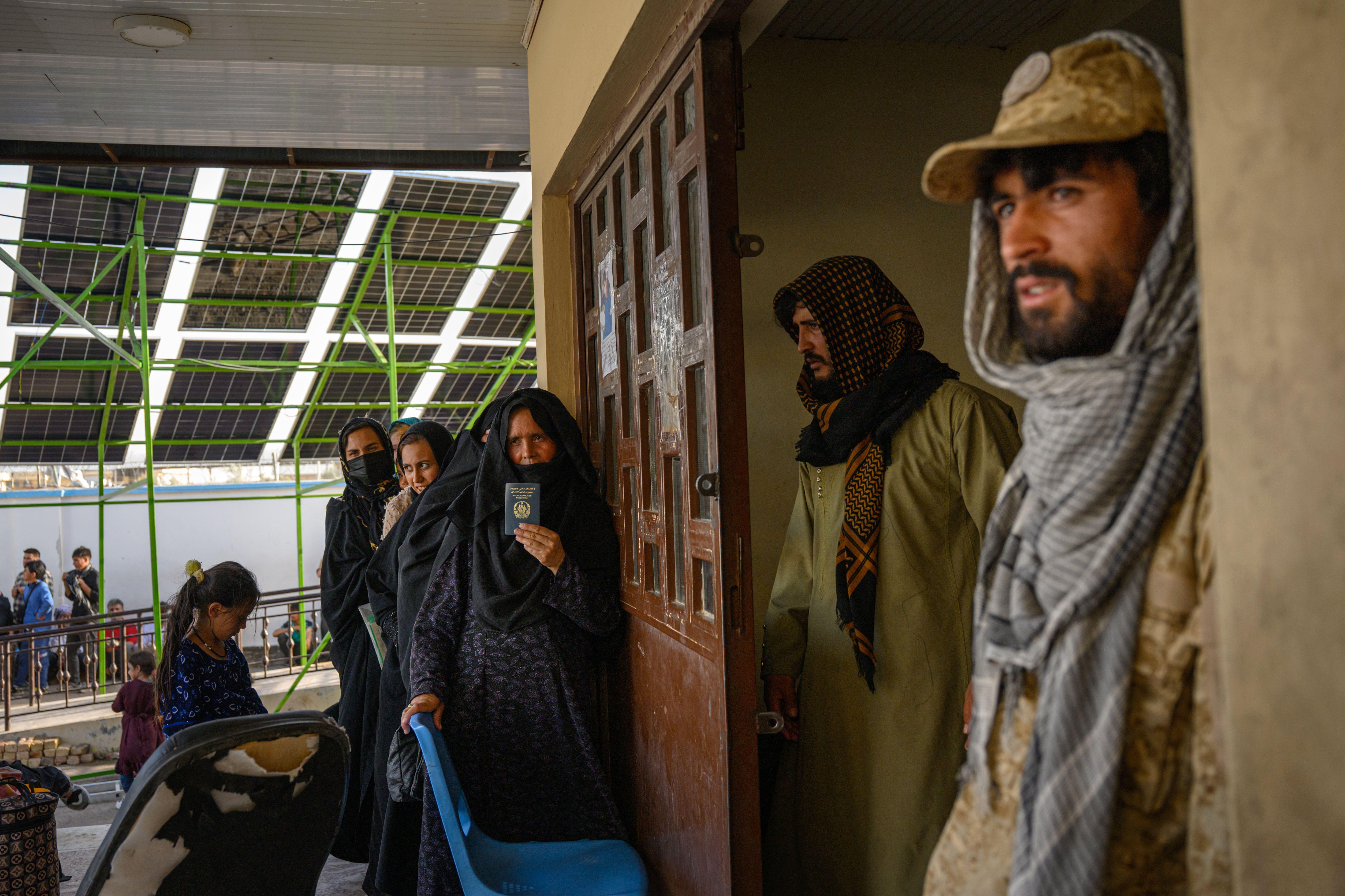 An Afghan woman who was recently deported from Tehran after living in Iran for 3 years, waits at the entrance of the reception center in Islam Qala