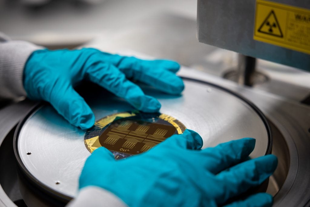 Two blue gloved hands handle a circular disc