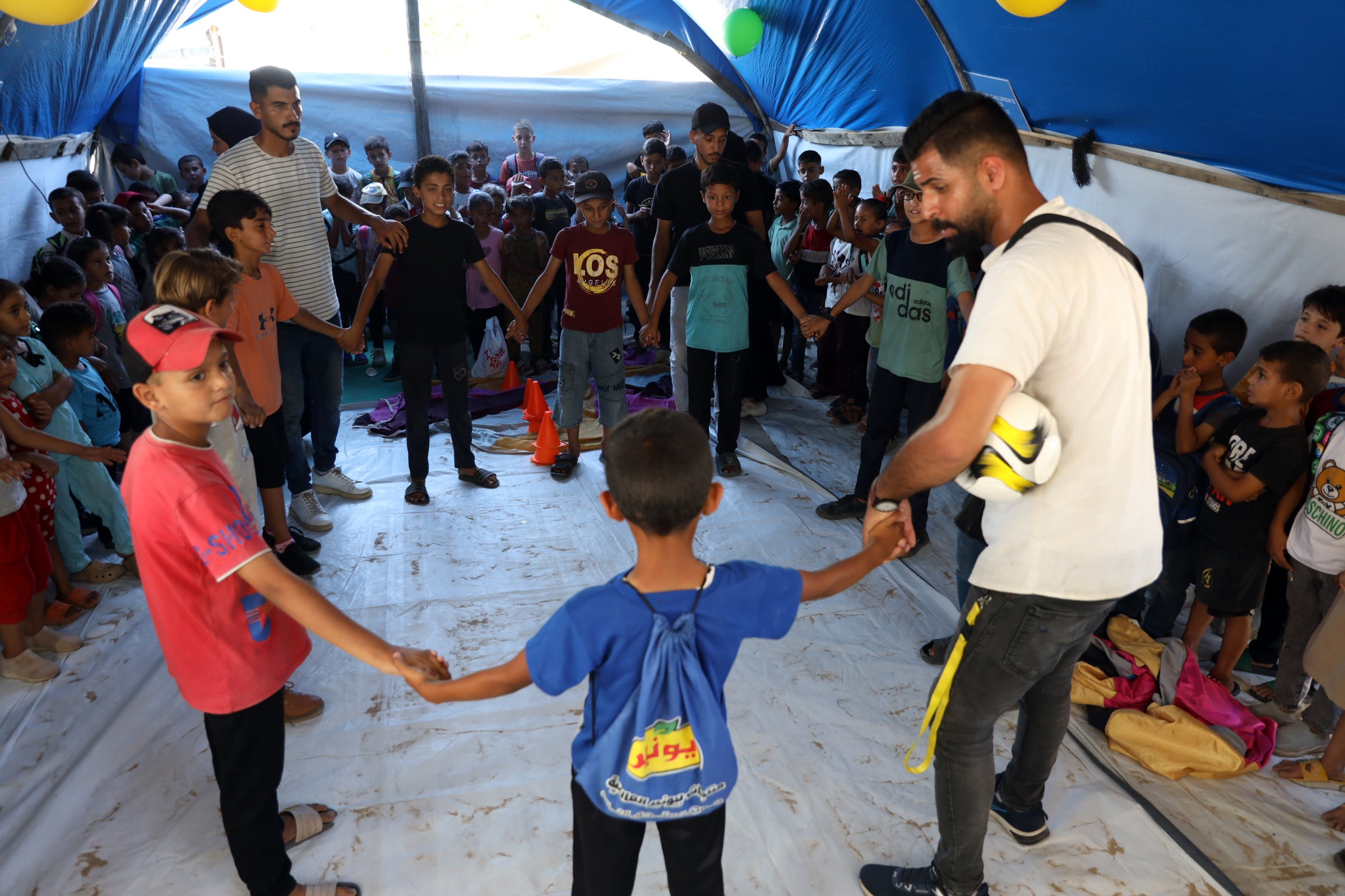 Children playing a game in a tent in Khan Younis
