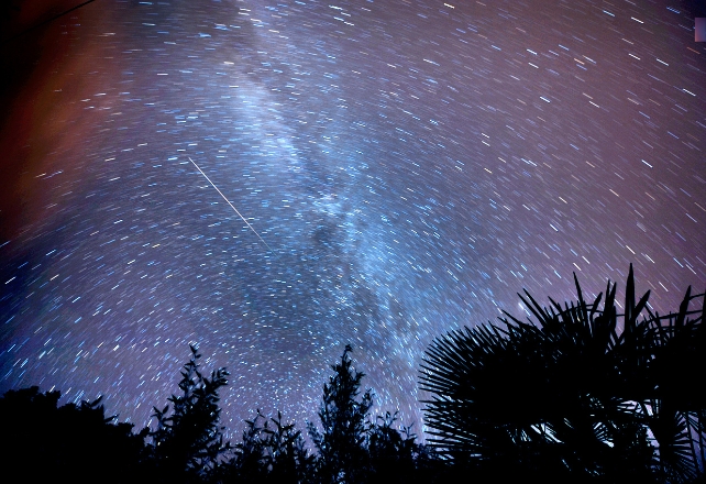 A meteor in the night sky with the Milky Way in the background