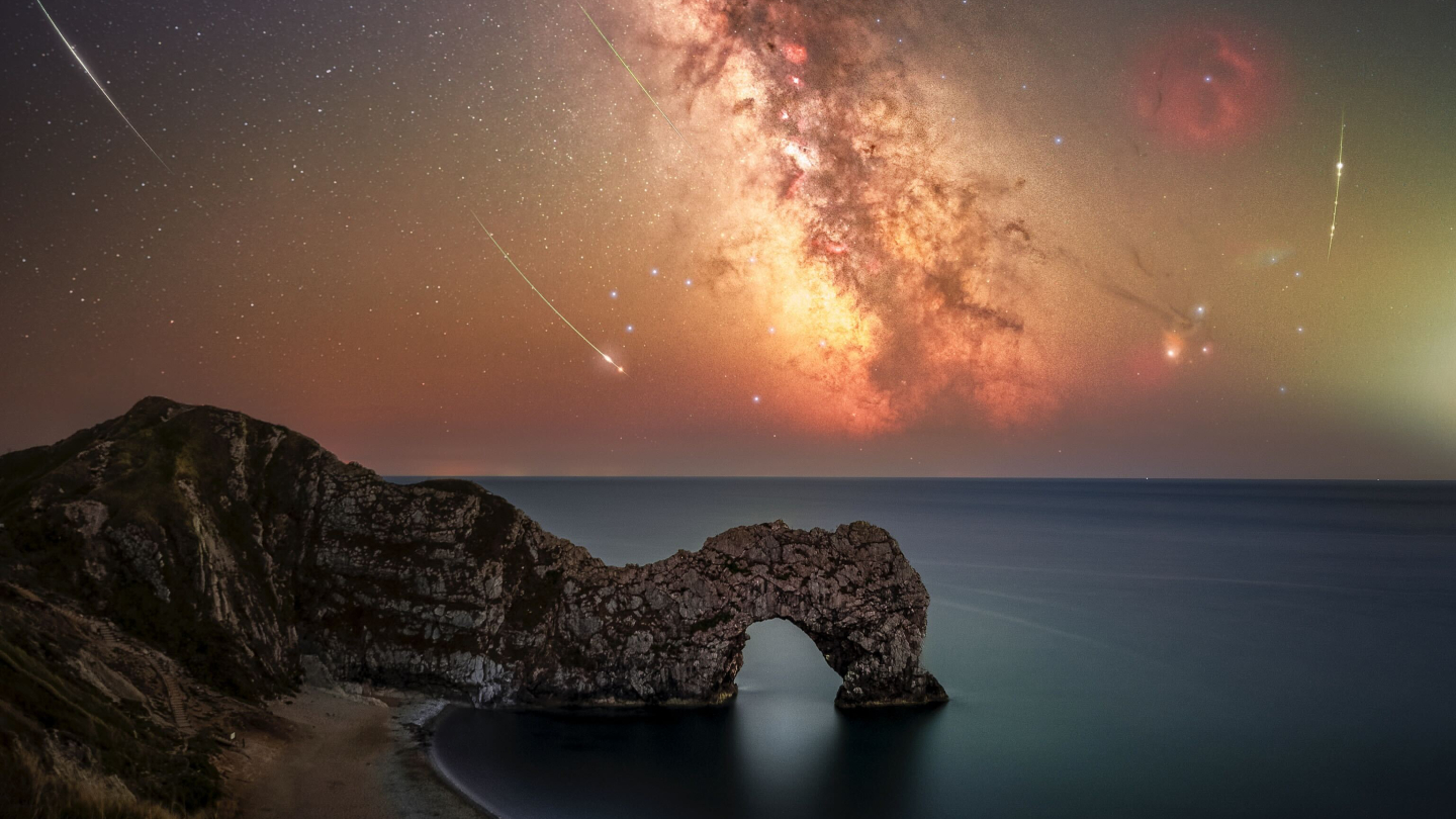 Perseid meteors are pictured alongside the Milky Way above a coastal scene featuring an arch-like rocky outcrop