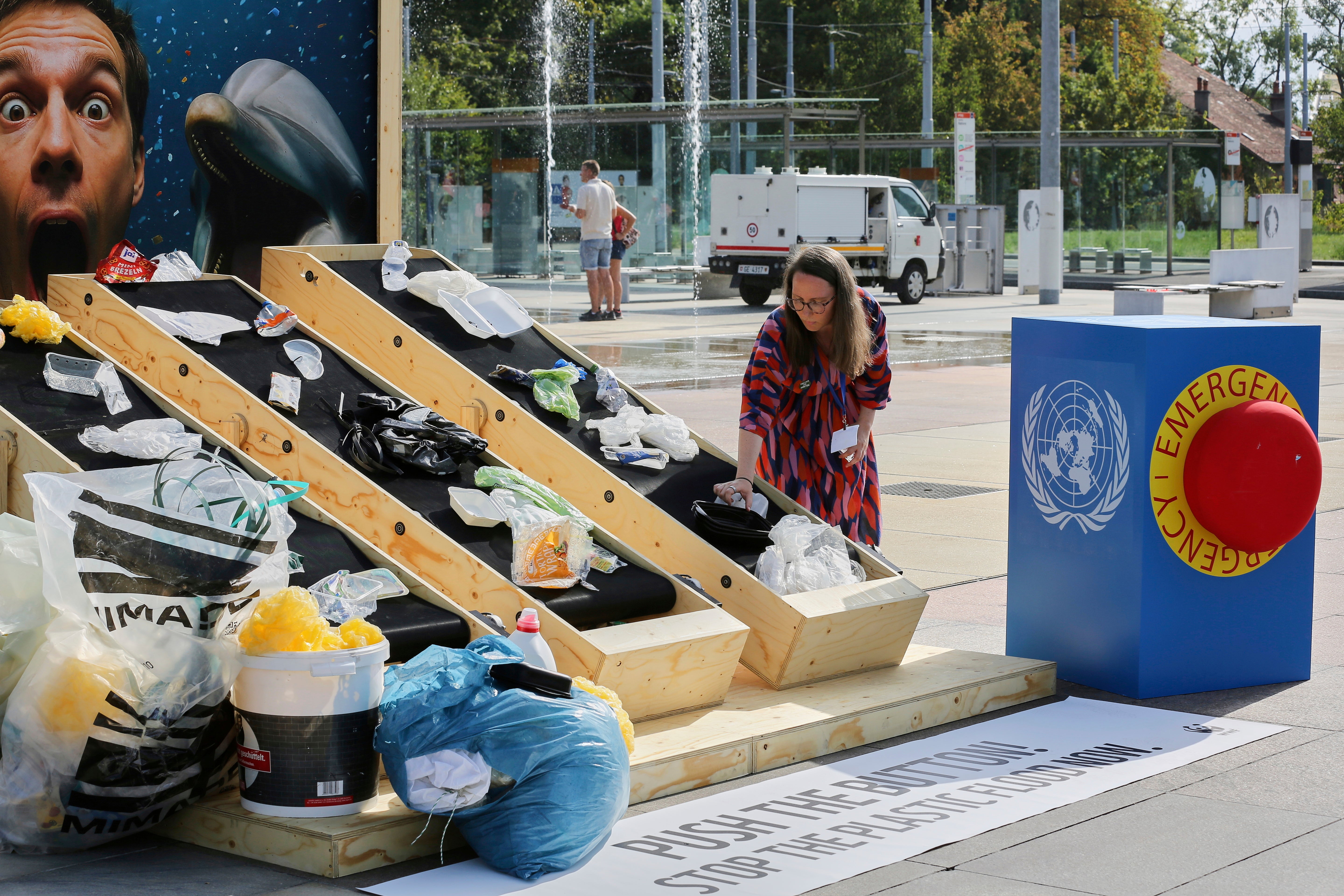 Hanna Eberhard of the World Wildlife Fund, arranges plastic waste on a conveyor belt display in front of the UN offices