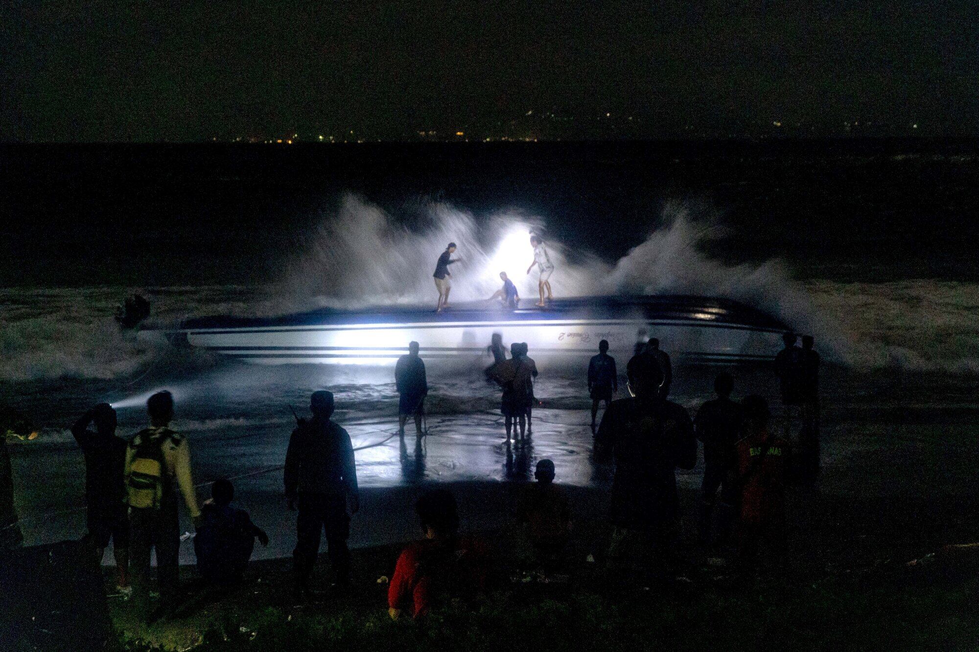  250806) -- BEIJING, Aug. 6, 2025 (Xinhua) -- People stand near the fast boat after it capsized at Sanur beach in Bali, Indonesia, Aug. 5, 2025. The Chinese consulate general in Denpasar, Bali, Indonesia, confirmed on Tuesday that two Chinese nationals were killed in a fast boat capsizing accident off Indonesia's Bali Island earlier in the day. (Photo by Dicky Bisinglasi/Xinhua) (Photo by Dicky Bisinglasi / XINHUA / Xinhua via AFP)