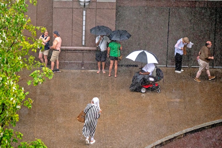 Pedestrians seek shelter from the rain Filbert Street near the Marriott hotel as storms hit the area Thursday afternoon July 31, 2025.