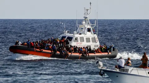 Reuters An Italian Coast Guard vessel carrying migrants rescued at sea passes near a tourist boat, on the Sicilian island of Lampedusa