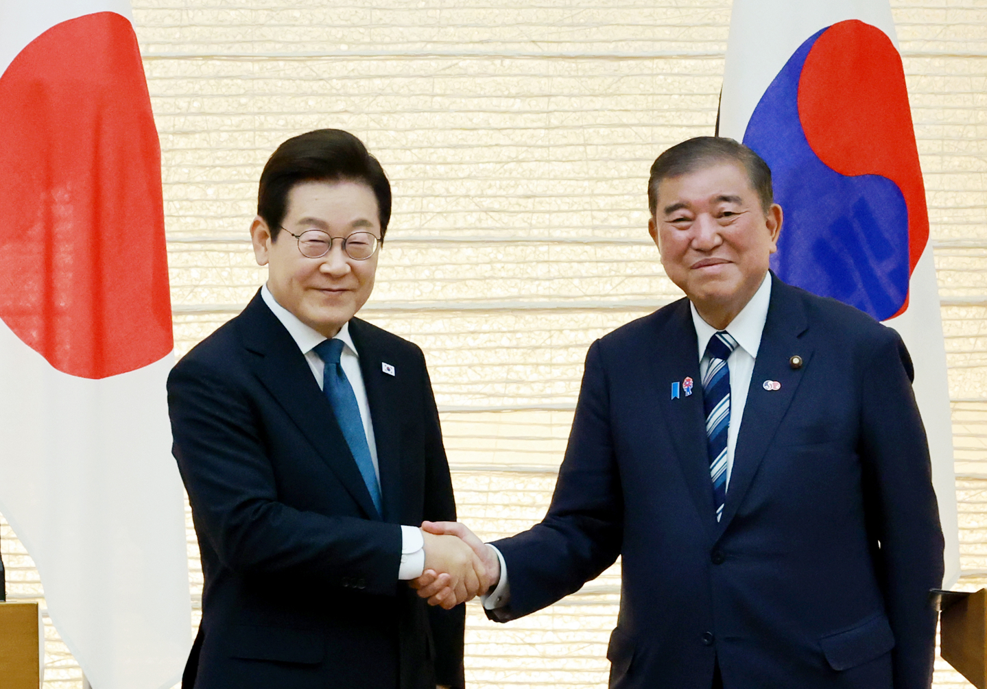 President Lee Jae Myung, left, and Japanese Prime Minister Shigeru Ishiba shake hands after their joint press briefing on the results of their bilateral summit at the prime minister's official residence in Tokyo on Aug. 23. [JOINT PRESS CORPS]