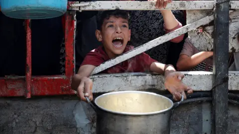 Reuters A Palestinian child is caught mid shout, eyes full of anguish, as he waits to receive food from a charity kitchen, amid a hunger crisis in Gaza