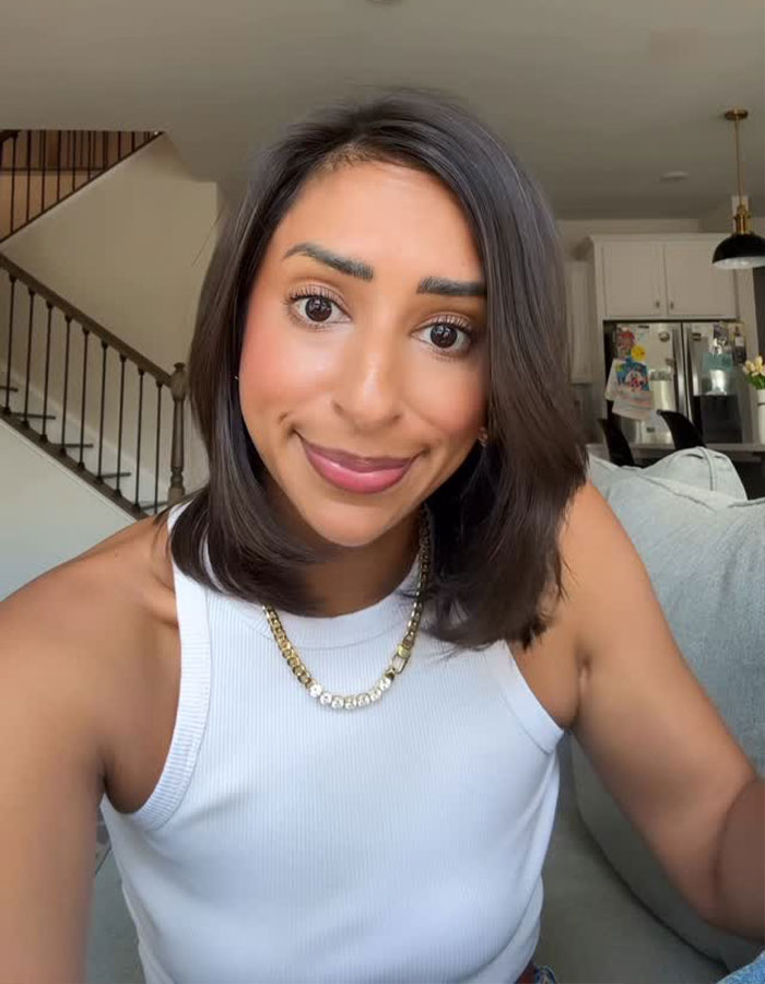 Woman with shoulder-length dark hair smiling indoors, related to Sweeney AE ad and woman jealous of appearance.