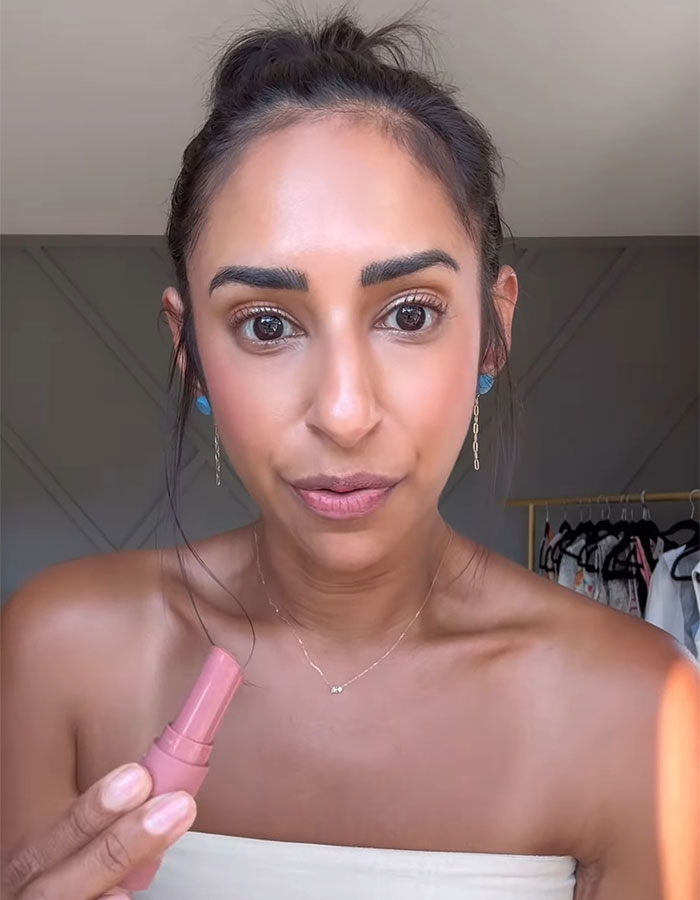 Woman holding makeup product, expressing emotion related to Sweeney AE ad controversy and jealousy topic.