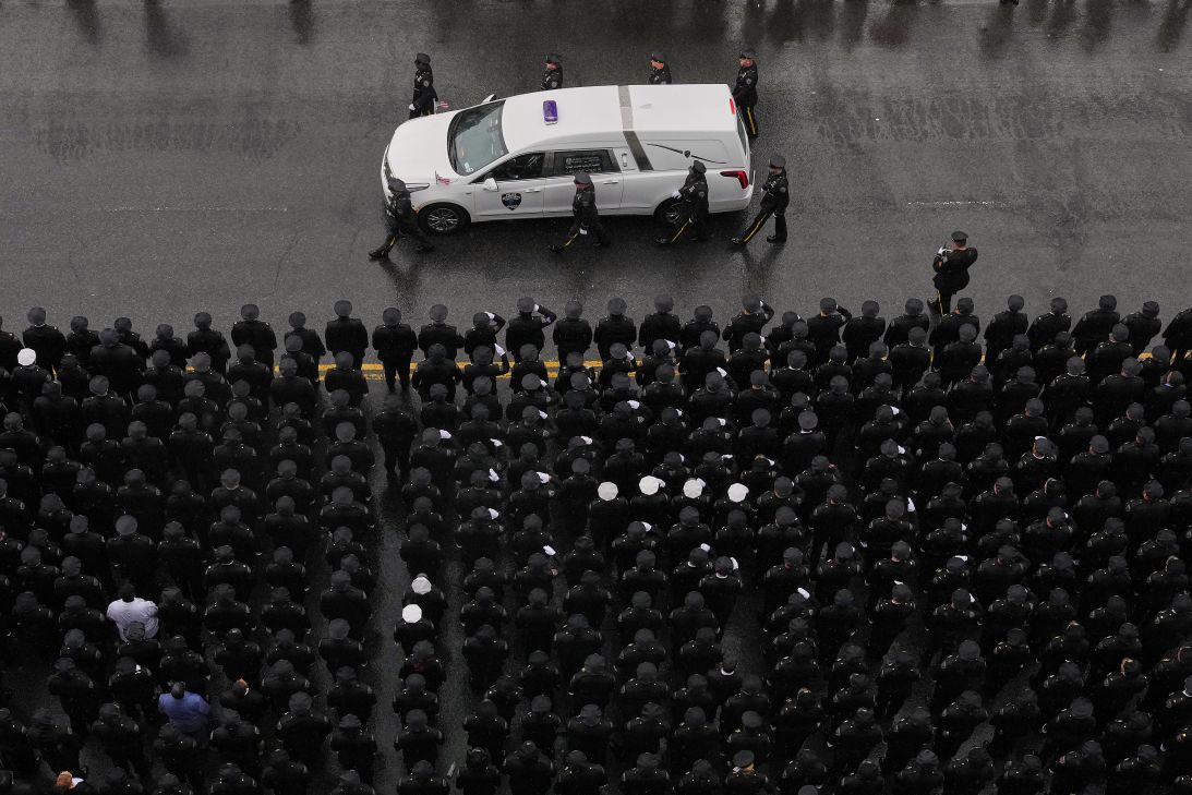 Officers flank each side of the white hearse carrying Islam's remains as it drives down White Plains Road after the funeral service on Thursday.