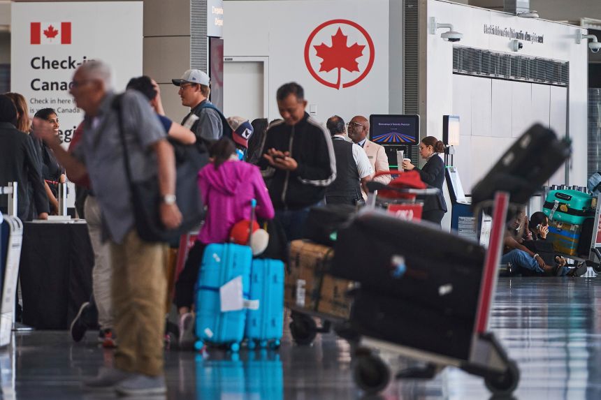 Travelers wait outside the Air Canada departure gates as flight attendants strike at Pearson International Airport in Toronto on August 16, 2025.