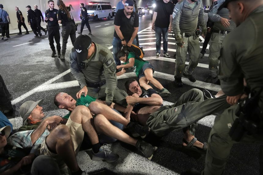 Police officers disperse demonstrators blocking a road during a protest in Jerusalem on Sunday.