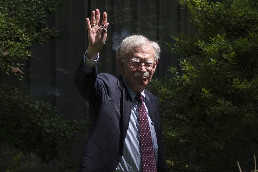 Former national security adviser John Bolton waves as he arrives at his house Friday in Bethesda, Maryland.