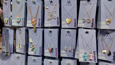 Grace Dean/BBC Rows of matching "best friends" necklaces on rails at Claire's, including butterflies, hearts and other designs