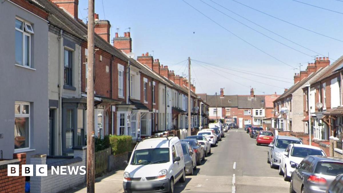 Cheverel Street is a residential road in Nuneaton with terraced houses and parked cars on both sides. There are speed bumps in the road. The houses have gardens with low walls outside. There are lampposts and hedges.