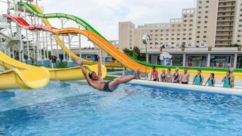 AFP Domestic tourists watch as a man uses a slide into a swimming pool at the Myongsasimni Water Park in the Wonsan Kalma Coastal Tourist Area in Wonsan, North Korea's Kangwon Province.