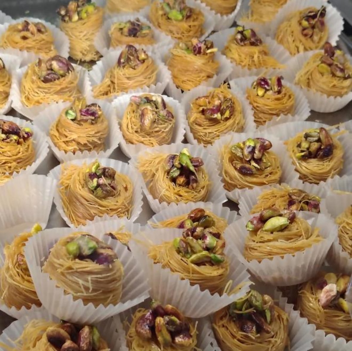 Rows of pistachio baklava in muffin liners. 