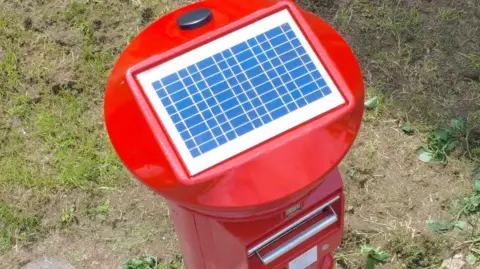 Royal Mail Bird's eye view of the new postbox design, showing the rectangular solar panel on the red roof of the pillarbox